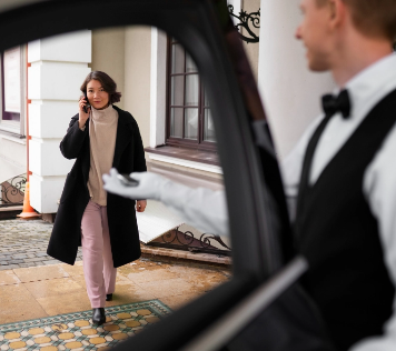 Chófer Alexandre Corporativa abre puerta a huésped corporativa en hotel.