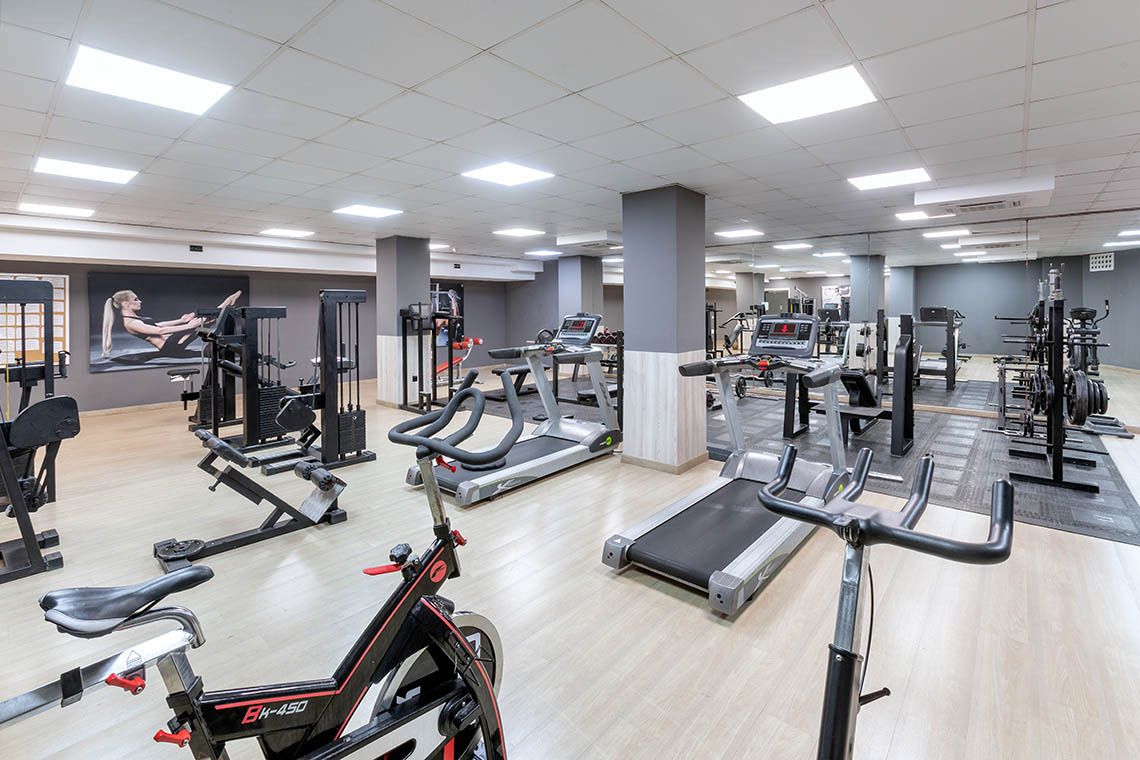 Modernes Hotel-Fitnessstudio Alexandre Corporativa mit Laufbändern, Gewichten und Fahrrädern für Gäste.
