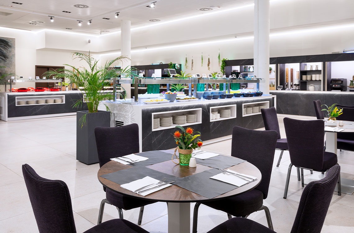 Buffet moderno y luminoso de Alexandre Corporativa, con mesas elegantes y una amplia selección de alimentos.