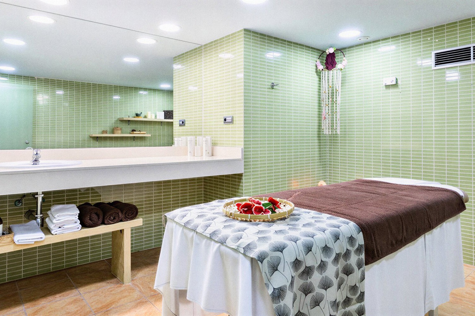 Spa moderno de Alexandre Corporativa con camilla, lavabo, toallas y azulejos verdes para relax.