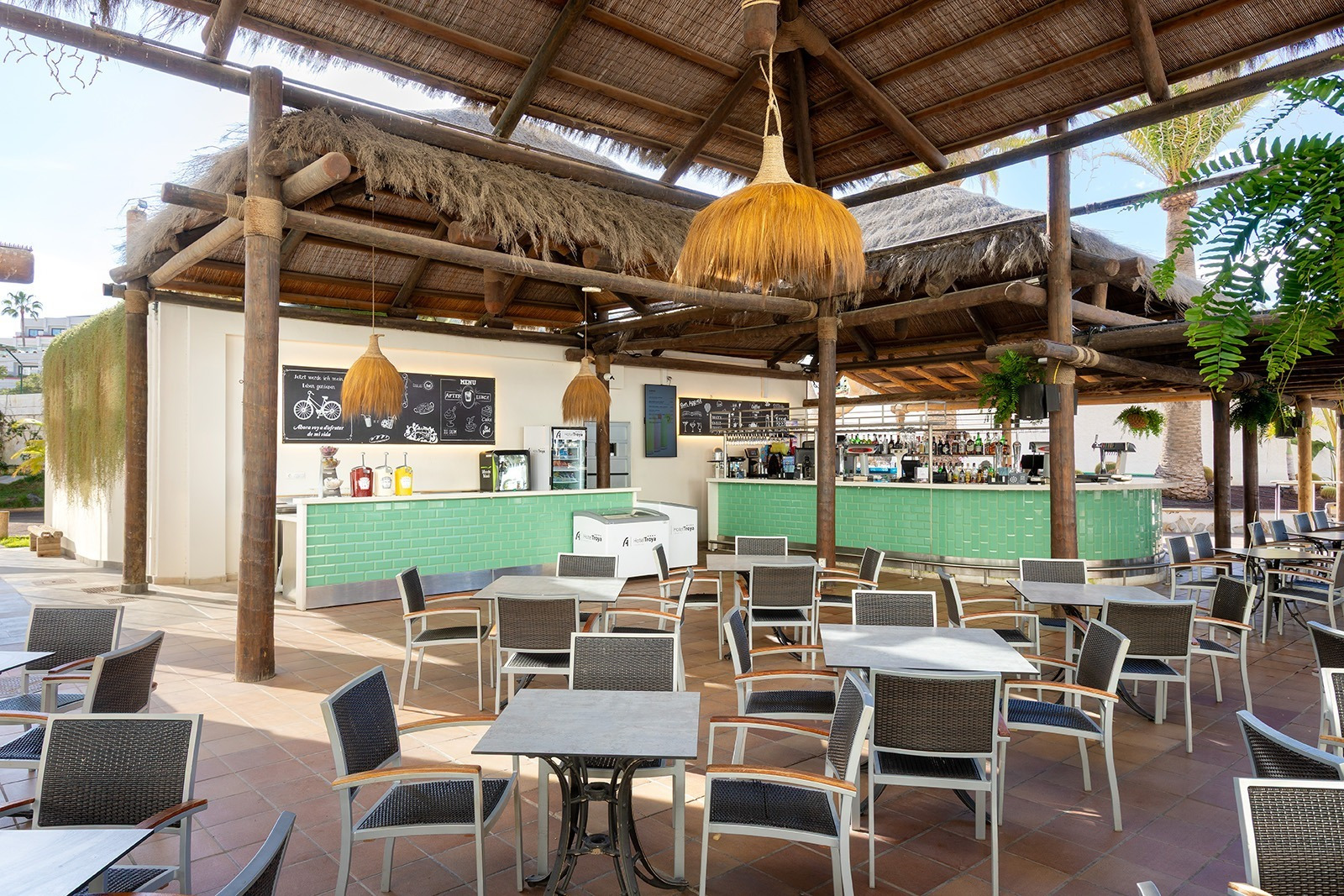 Alexandre Corporativa's outdoor bar and restaurant with thatched roof, green counter, and comfortable seating.