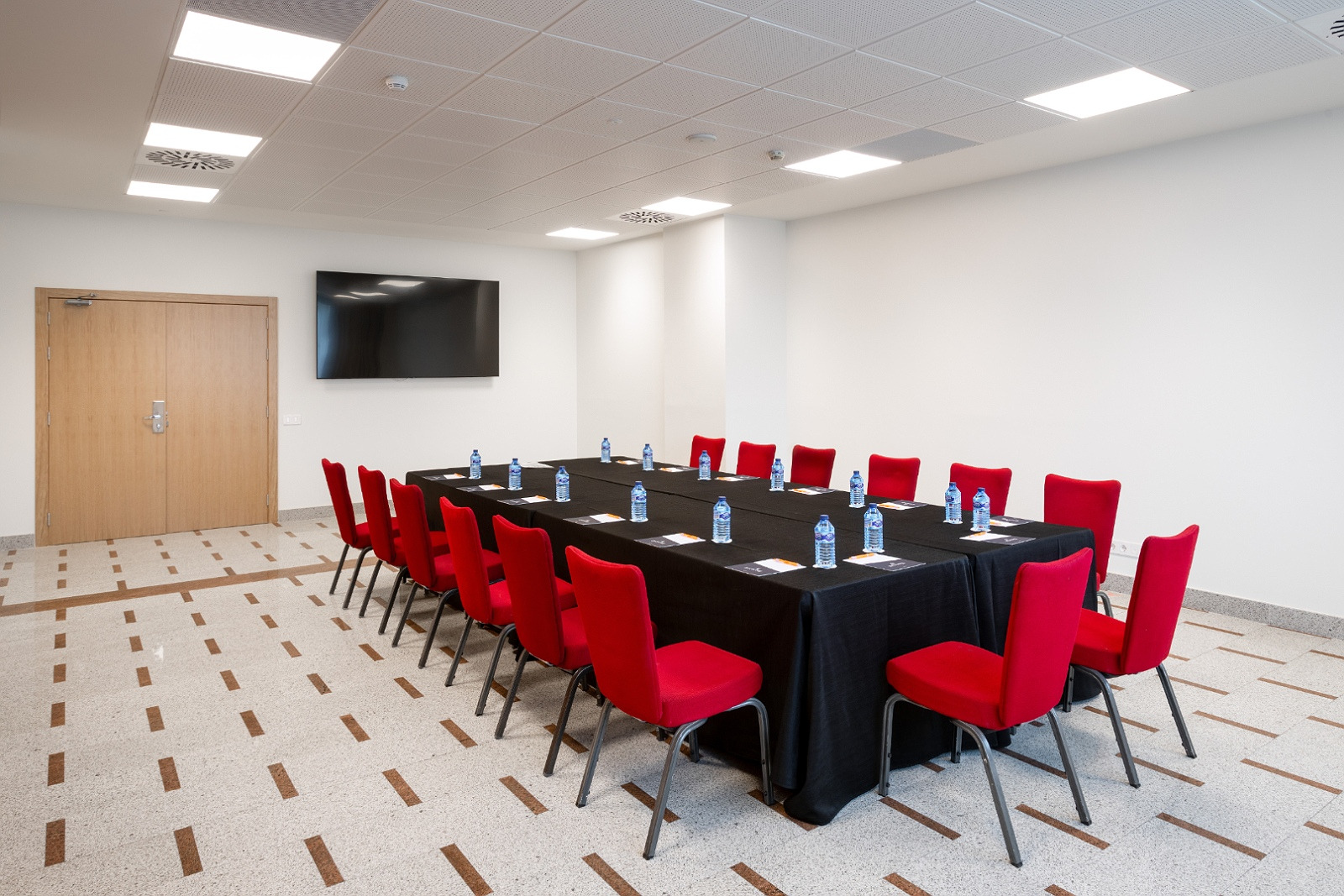 Sala de eventos Alexandre Corporativa con mobiliario moderno y proyector, ideal para reuniones.