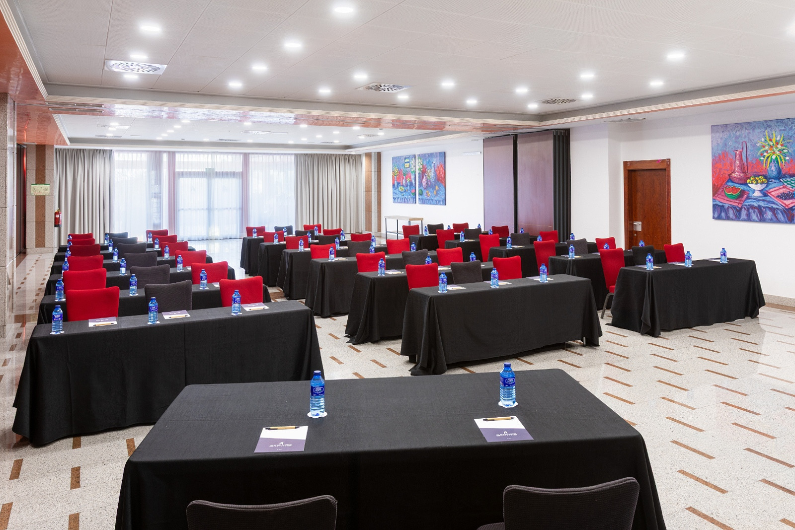 Sala de reuniones Alexandre Corporativa con mesas en U, sillas, proyector y luz natural.