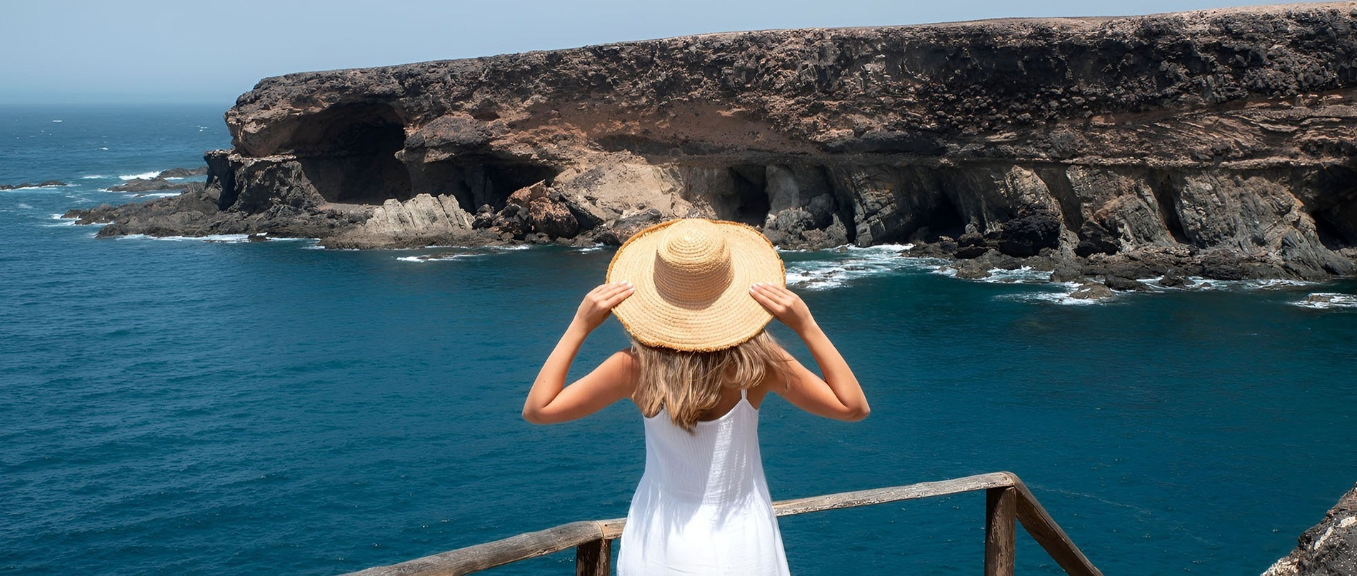Woman enjoying ocean view from cliffs, reflecting Alexandre Hotels' Sustainability & Quality.