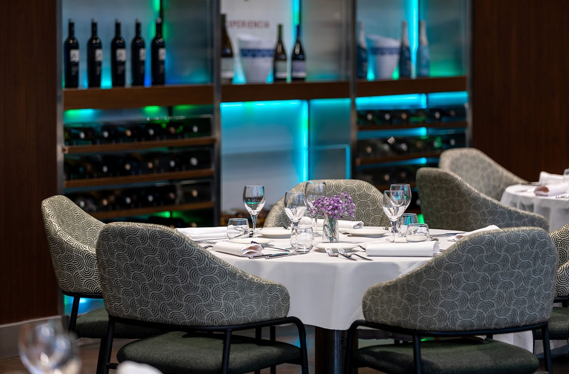 Mesa de comedor grande en espacio Alexandre Corporativa, con mantelería turquesa y vistas al jardín.