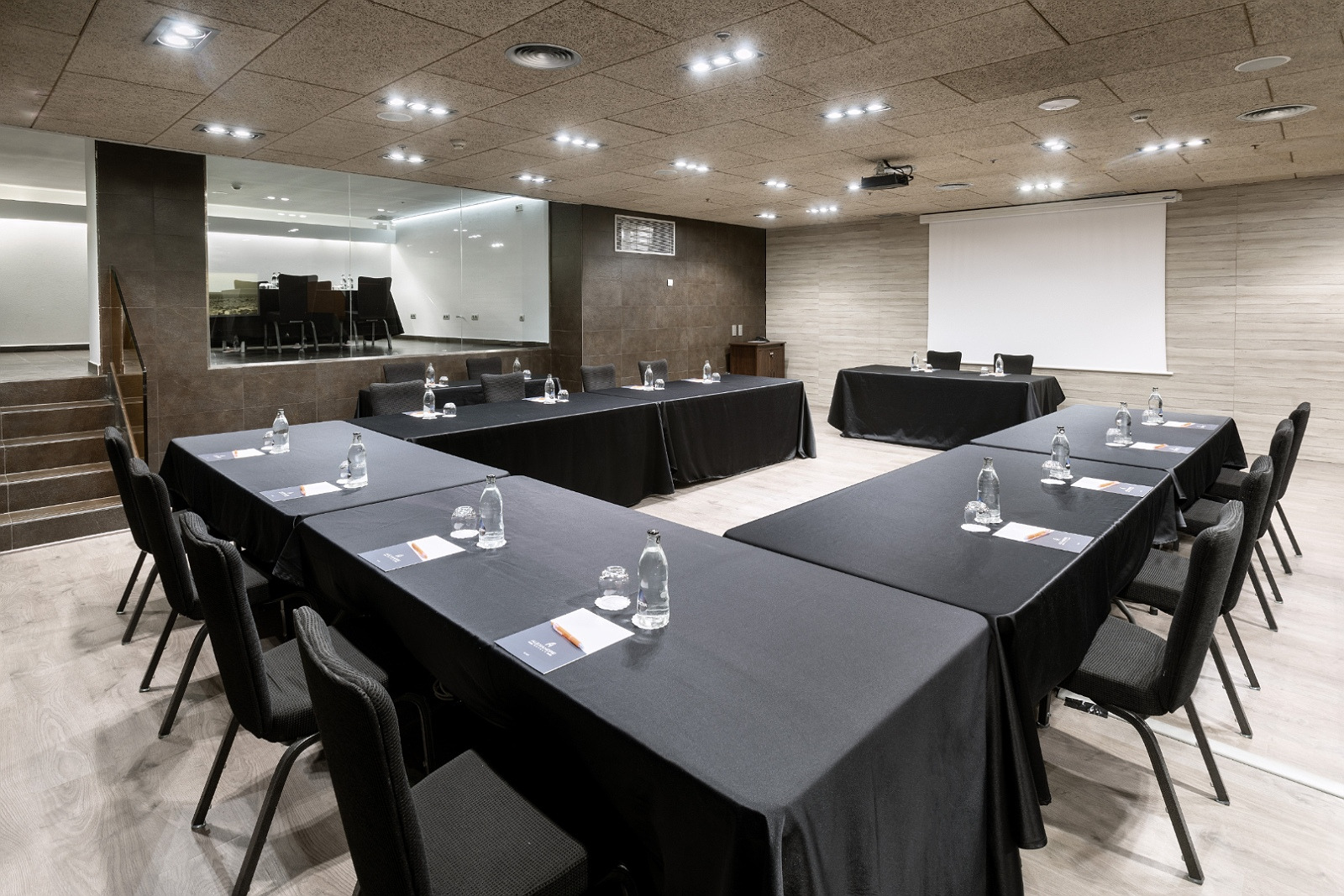 Salle de réunion Alexandre Corporativa moderne avec tables noires et sièges.