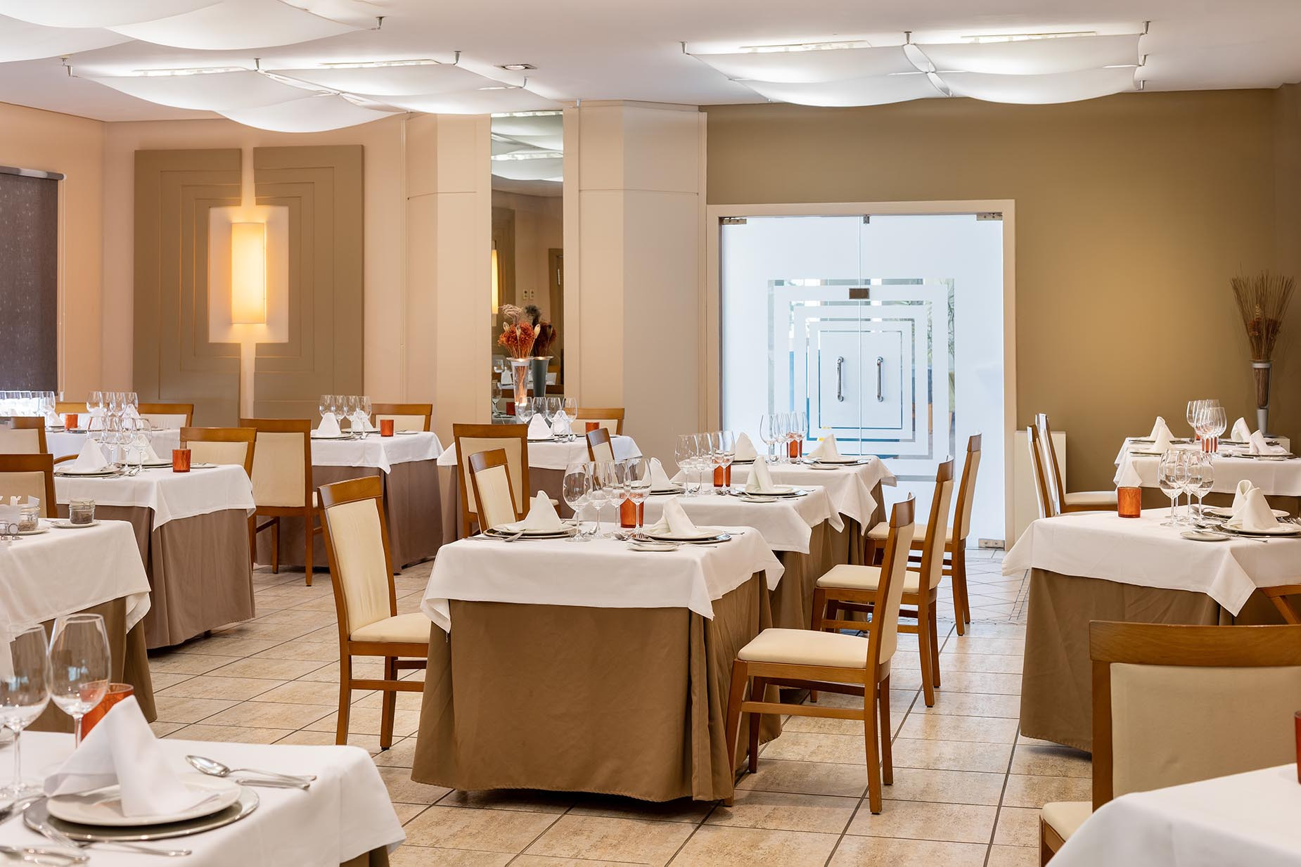 Helles Hotelrestaurant von Alexandre Corporativa mit Meerblick, eleganten Tischen und modernen Hängelampen.