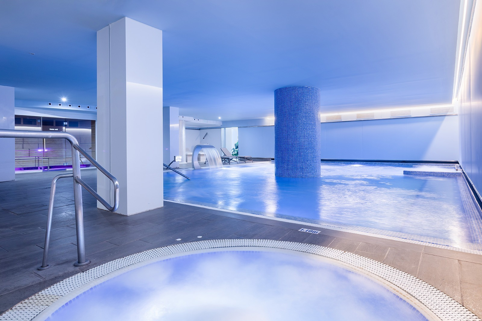 Piscina y spa moderno de Alexandre Corporativa con jacuzzi e iluminación azul.