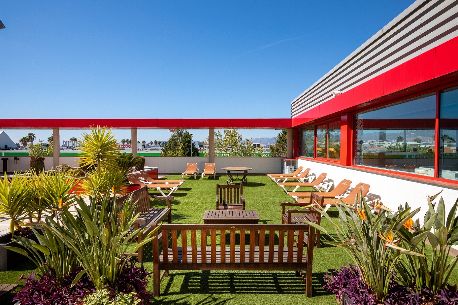 Terraza del Alexandre FrontAir Congress: tumbonas, bancos y plantas bajo el sol.