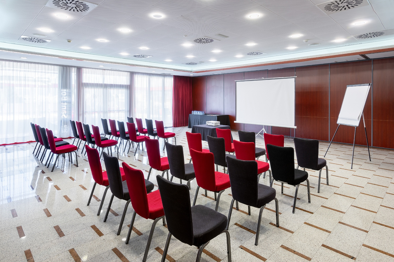 Moderna sala de reuniones Alexandre Corporativa con mesas, sillas, pantalla y luz natural. Ideal para eventos.
