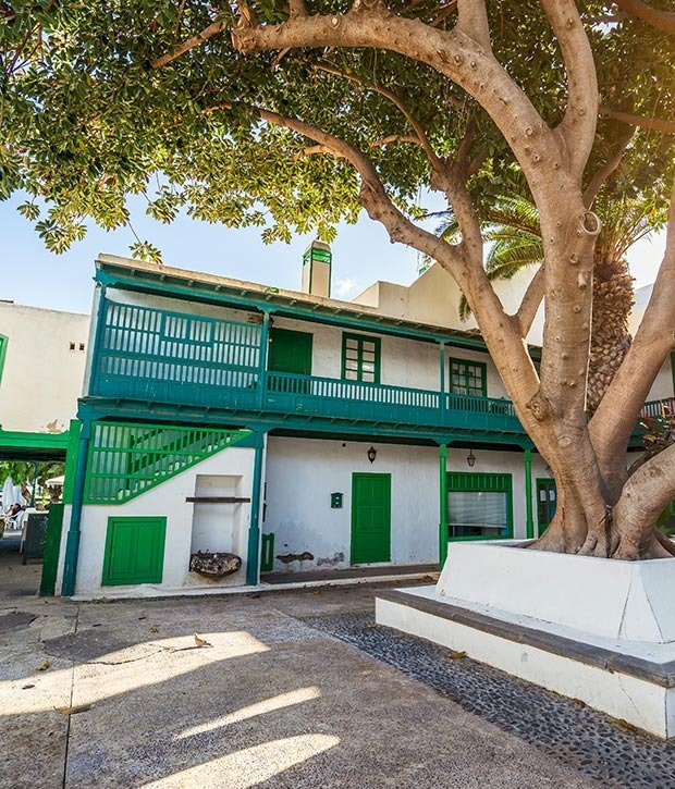 Hotel Alexandre Corporativa: edificio tradicional con balcones verdes y árbol.