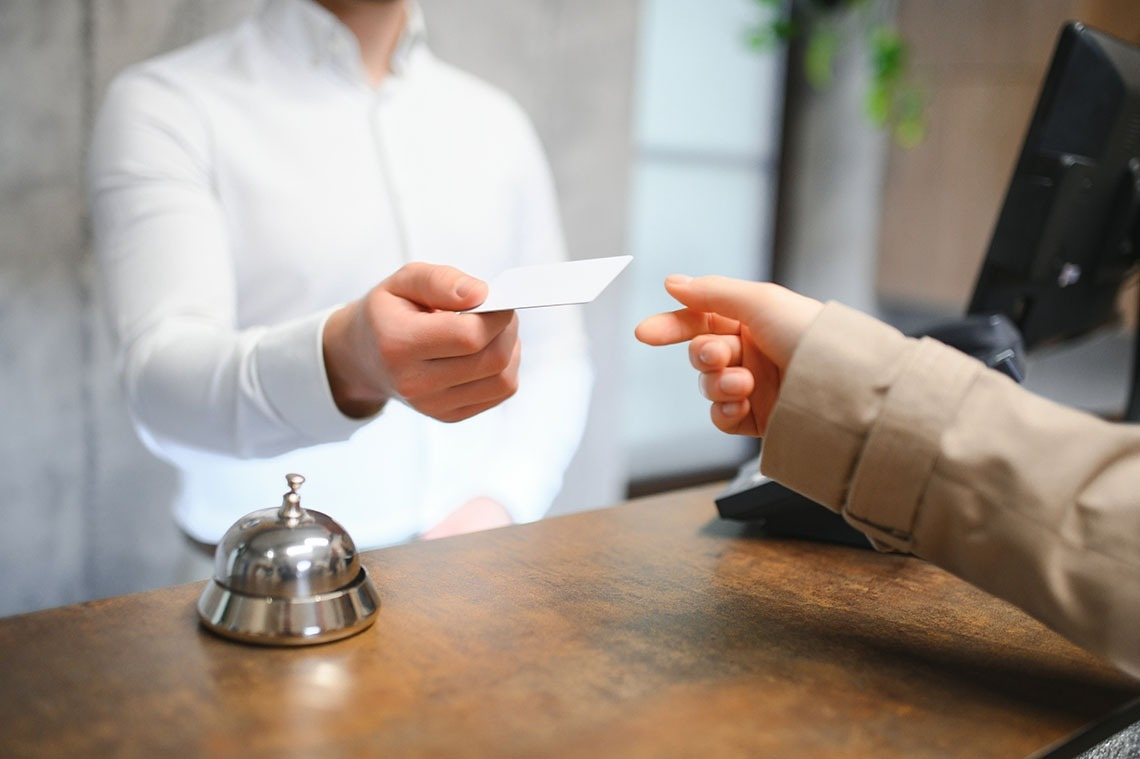 Alexandre Corporativa hotel check-in: staff hands key card to guest.