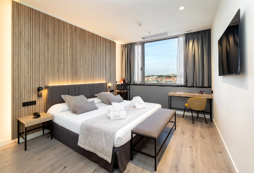 Habitación moderna del hotel Alexandre Corporativa con cama king, vistas a la ciudad y decoración elegante.