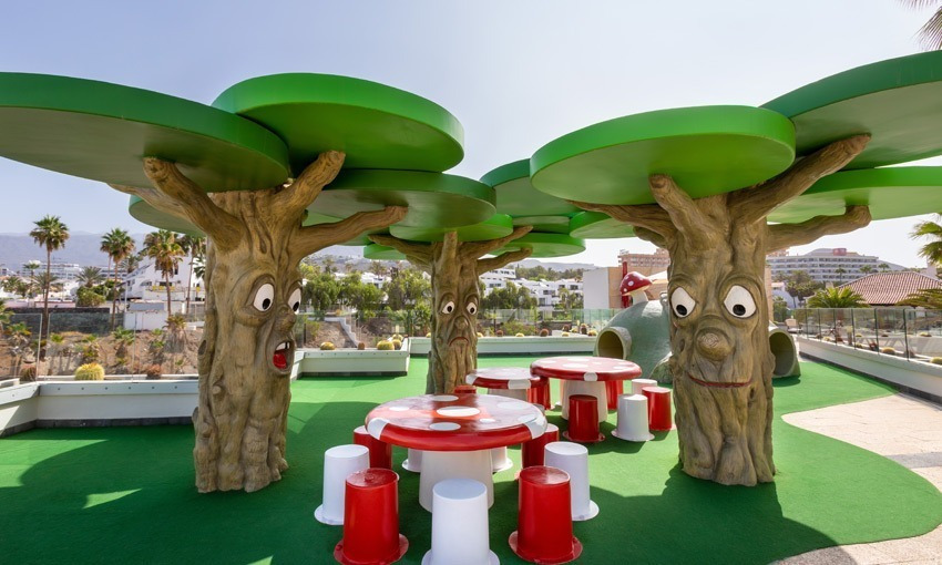 Kinderspielbereich im Freien mit Märchenbaum-Strukturen und Pilz-Tischen bei Alexandre Corporativa.