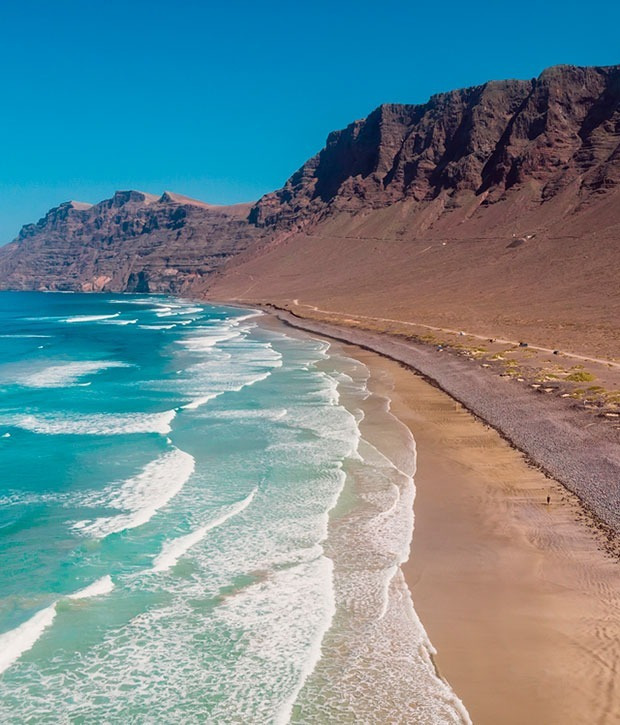 Magnífica playa con olas y acantilados rocosos, un destino inspirador para Alexandre Corporativa.
