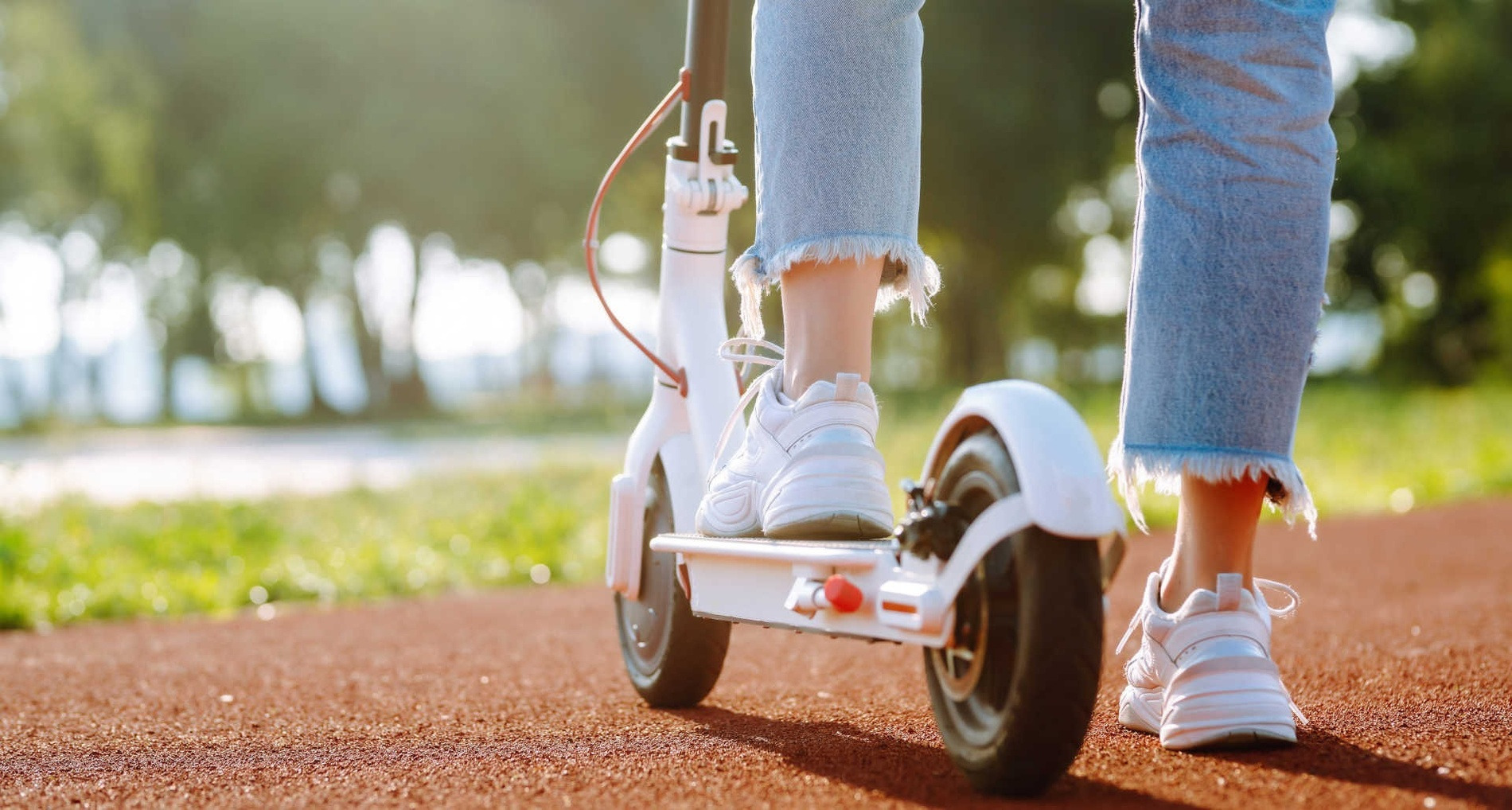 Feet on electric scooter on a sunny path, reflecting Alexandre Hotels' Electric Vehicle Policy.