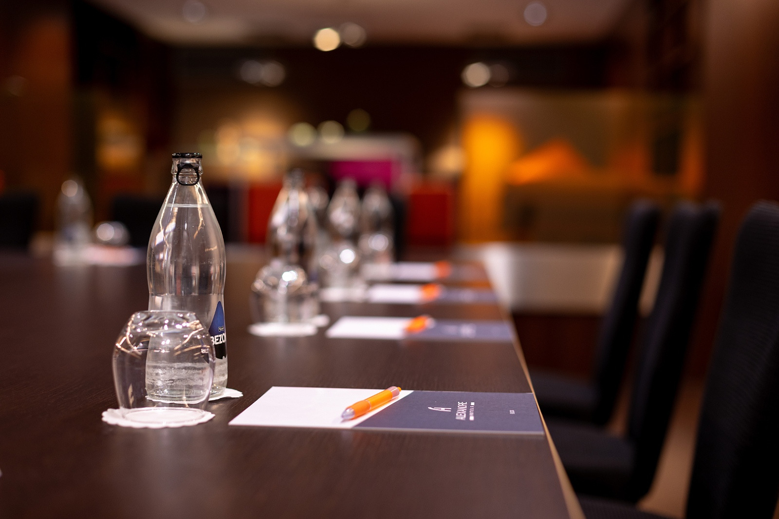 Table de réunion prête pour événement Alexandre Corporativa avec bouteilles d'eau et stylos.