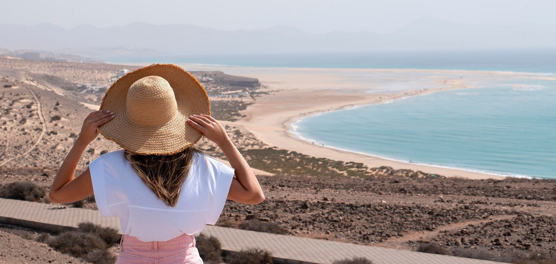 Femme au chapeau admirant la plage et l'océan turquoise. Hôtels à Tenerife Sud | Alexandre Hotels.