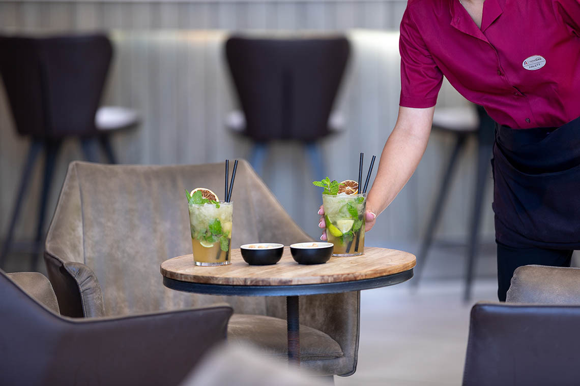 Barman garnissant un cocktail fleuri, parfait pour un événement Alexandre Corporativa.