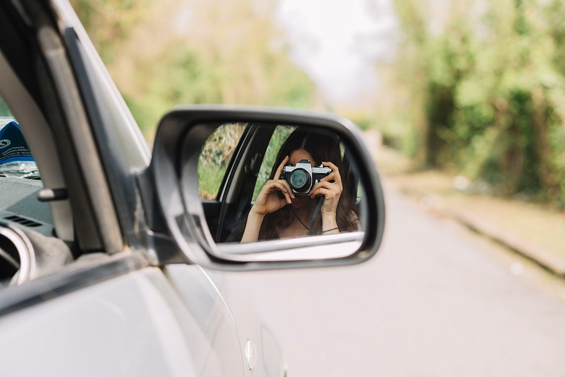 Photographe en voiture, reflet dans le rétroviseur. L'aventure selon Alexandre Corporativa.