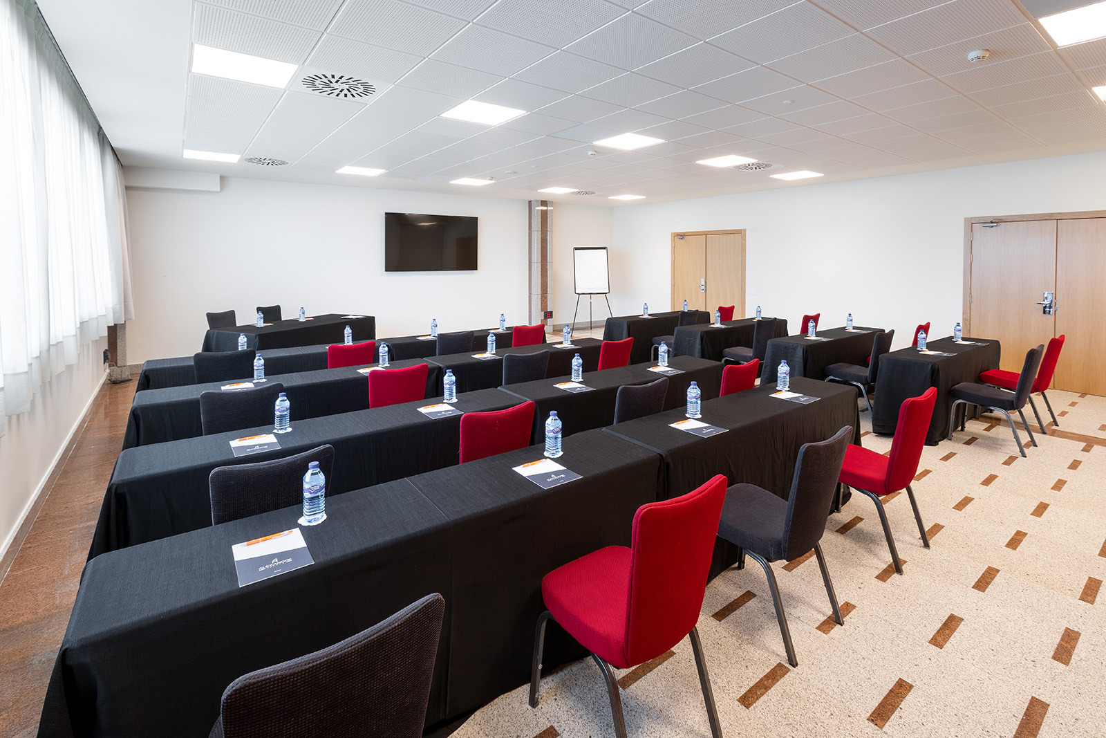 Sala de reuniones moderna en Alexandre Corporativa, equipada para eventos con sillas rojas y negras.