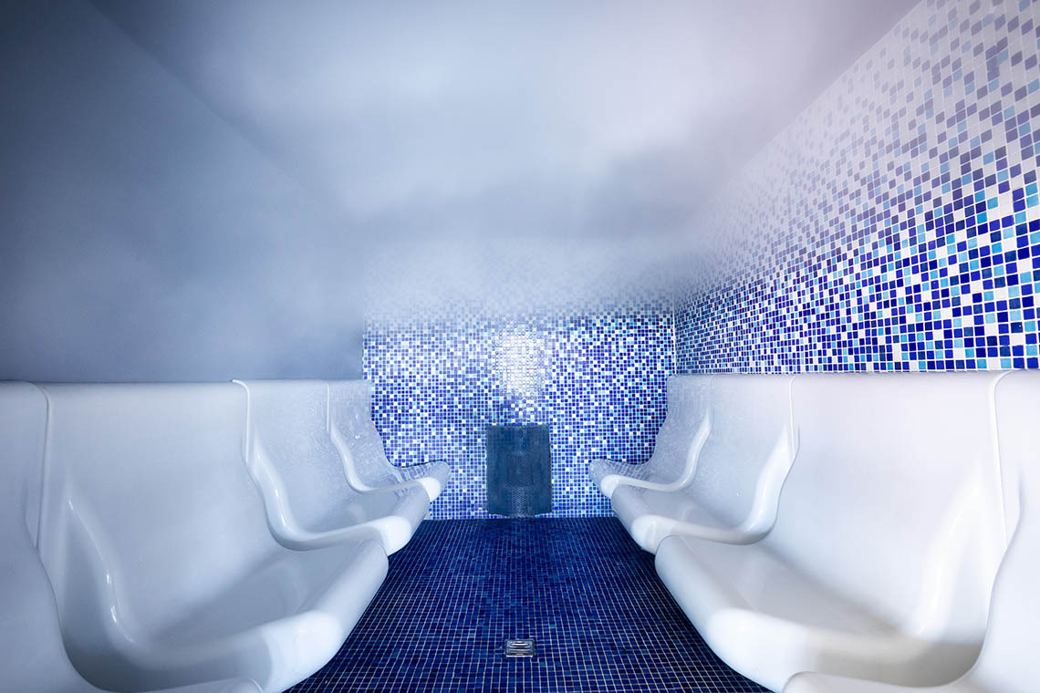 Hammam luxe avec mosaïques bleues et sièges blancs, parfait pour le spa Alexandre Corporativa.