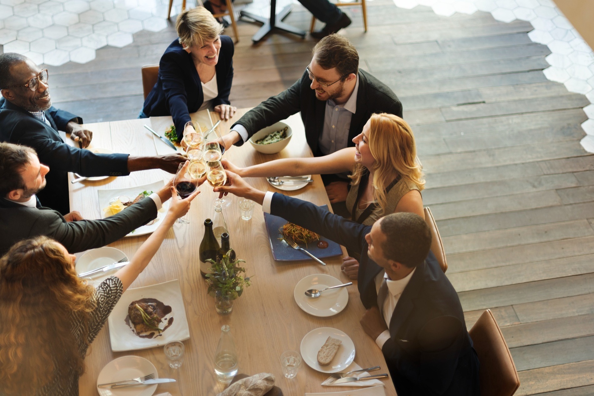 Smiling guests toasting at a dinner table, perfect for Alexandre Hotels groups and events.