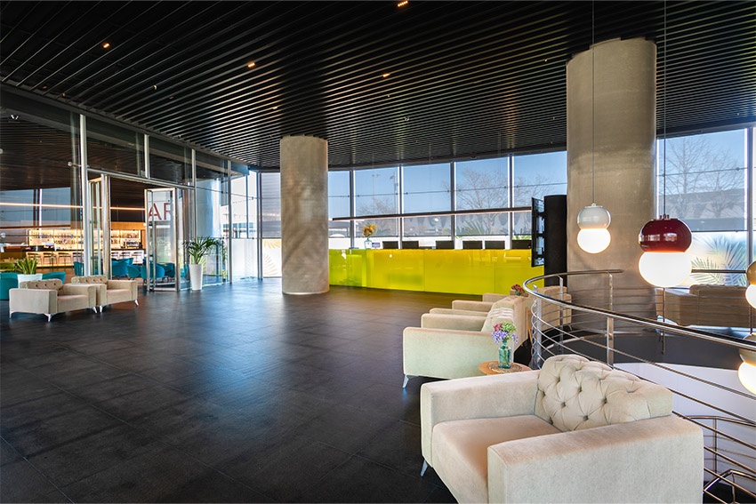 Lobby del hotel Alexandre Fira Congress con sofás y recepción amarilla.