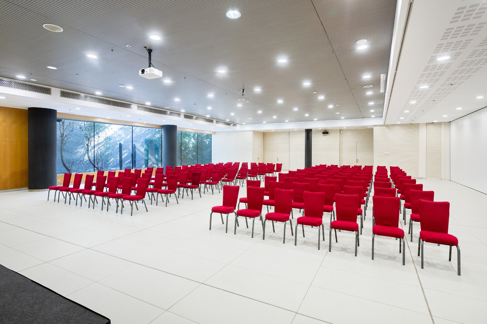 Salle de conférence Alexandre Corporativa avec sièges rouges et projecteur.