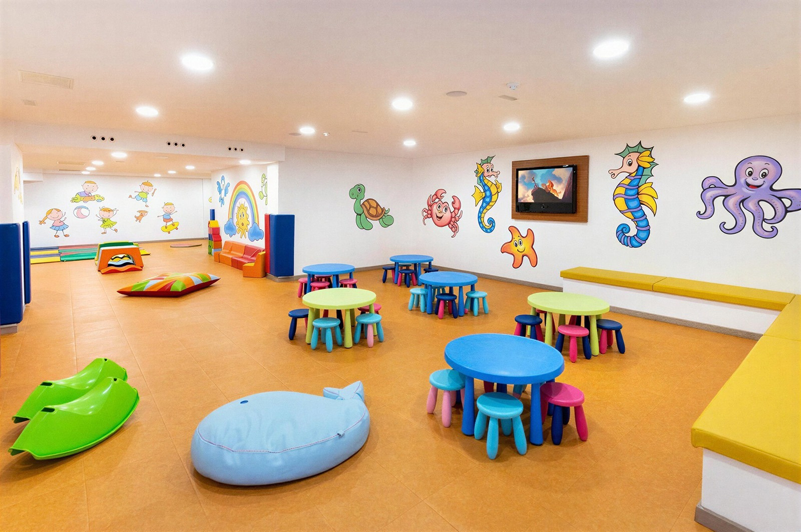 Alexandre Corporativa Kinderclub: Bunter Spielbereich mit Tischen, Stühlen & Meerestieren.