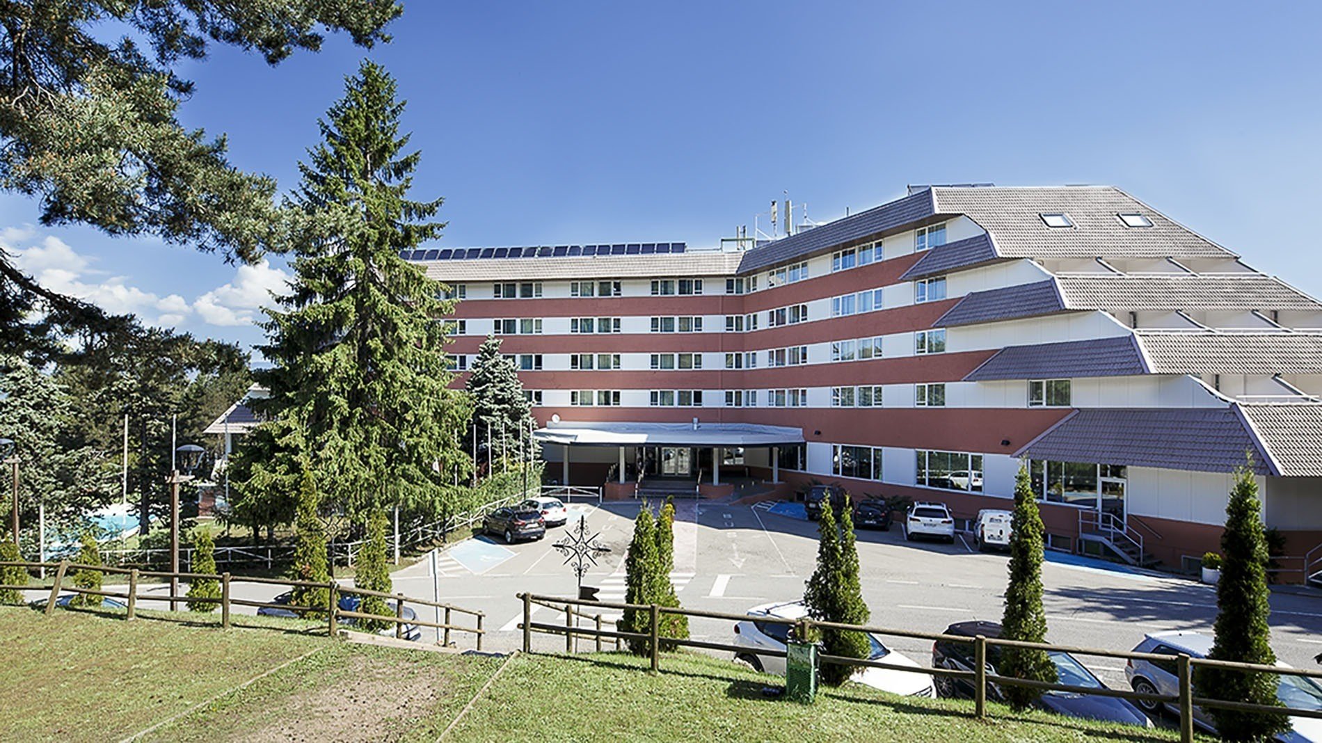 un grand bâtiment rouge et blanc avec des voitures garées devant