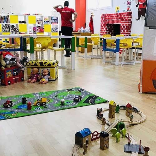 una sala de juegos con un camión de bomberos y un tren de madera