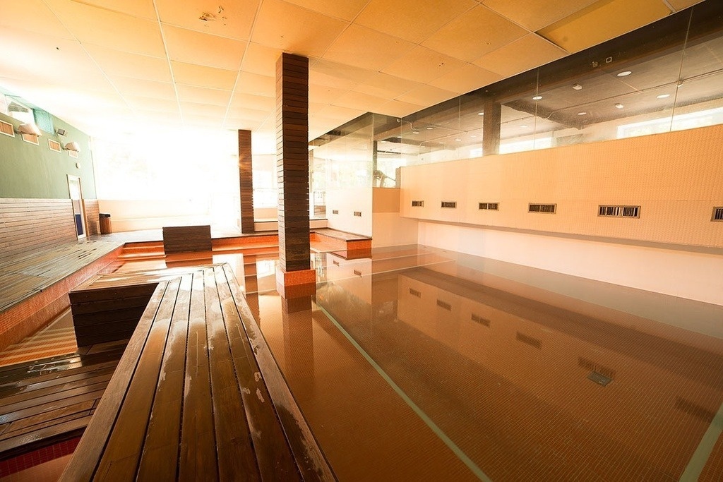 a large room with a swimming pool and a wooden bench