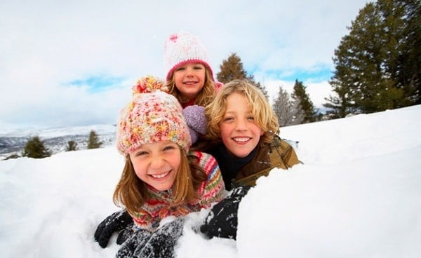 a boy and two girls are playing in the snow