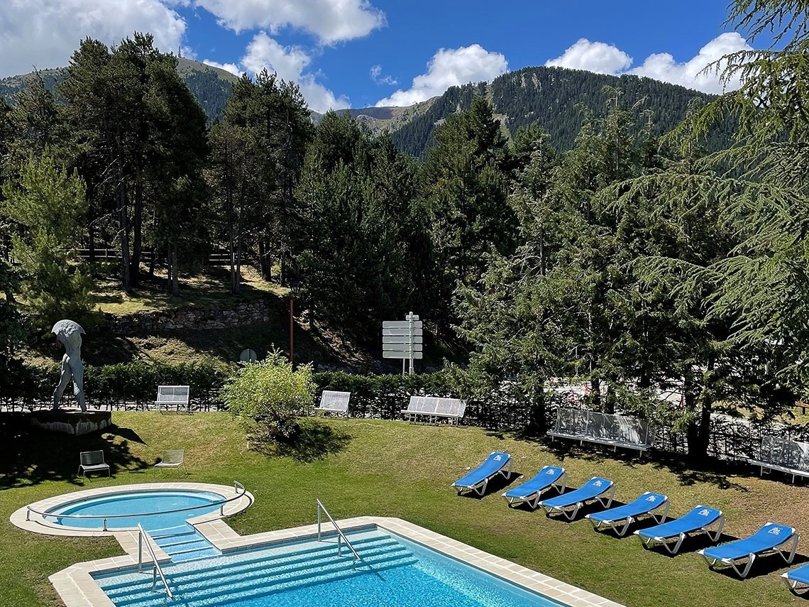 una piscina rodeada de sillas y árboles con una montaña al fondo