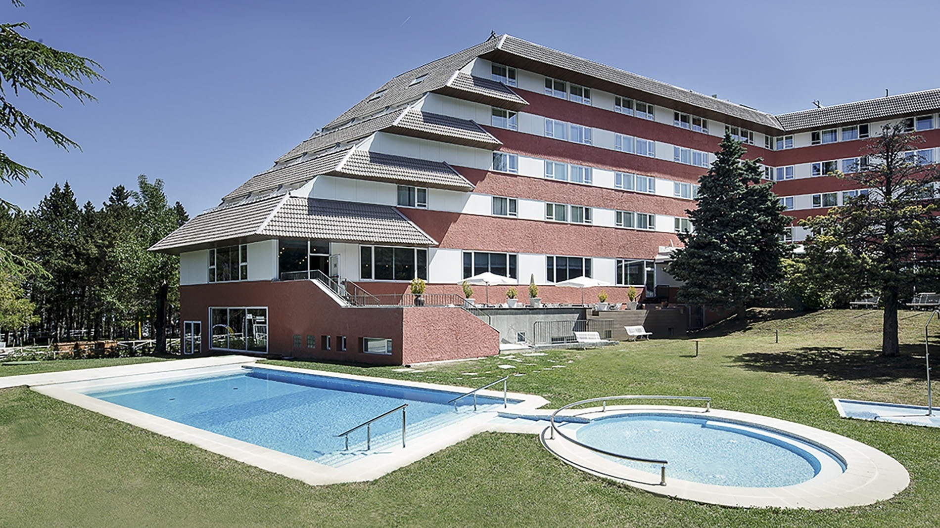 un gran edificio rojo y blanco con una piscina al frente