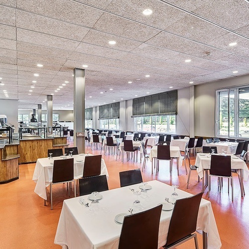 un restaurante lleno de mesas y sillas con mantel blanco