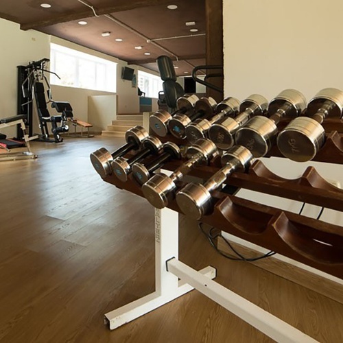 un montón de mancuernas están en un rack de madera en un gimnasio