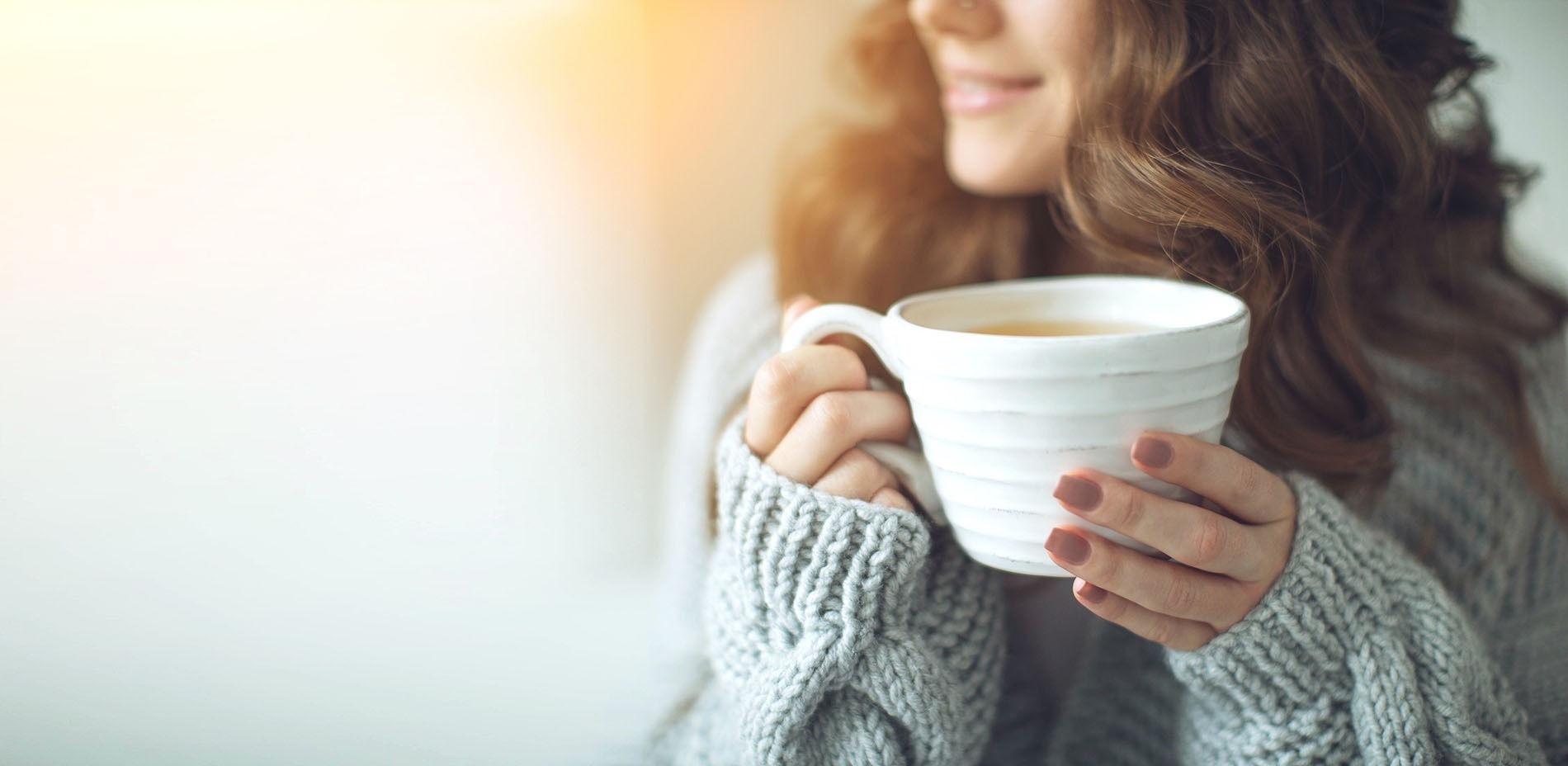 una mujer sostiene una taza de café en sus manos