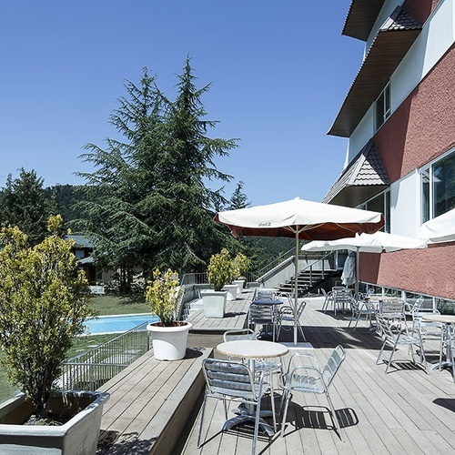 una terraza con mesas y sillas y sombrillas y una piscina en el fondo