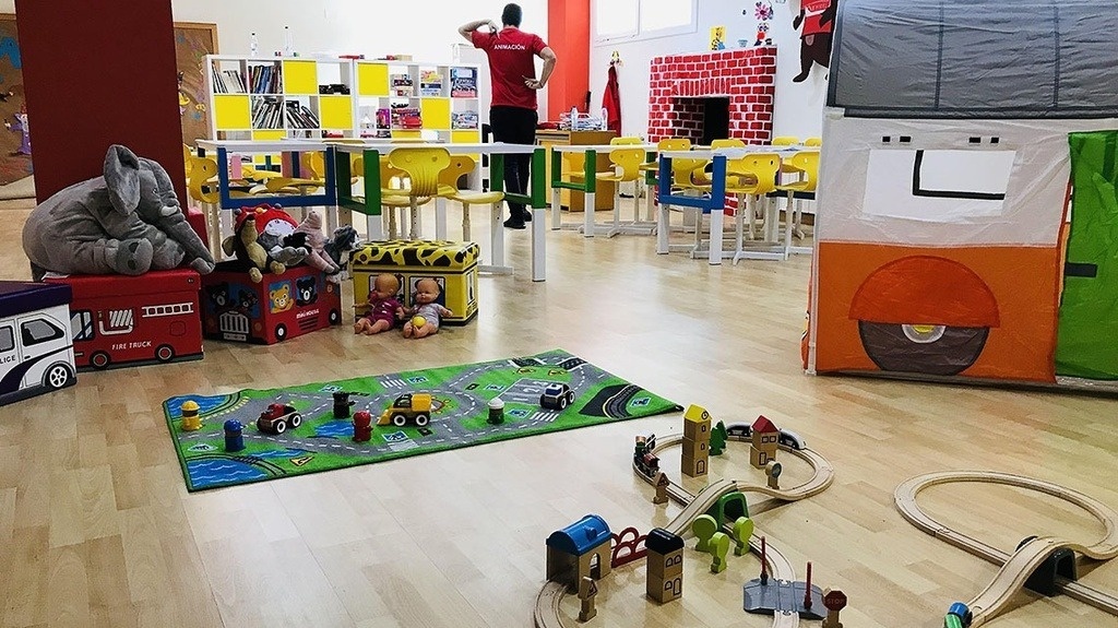 a man in a red shirt stands in a room filled with toys