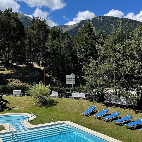 una piscina rodeada de sillas de playa y una montaña en el fondo