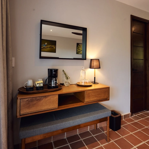Alto Monte: cafetera y tazas en tocador de madera con espejo, cortesía de hotel.