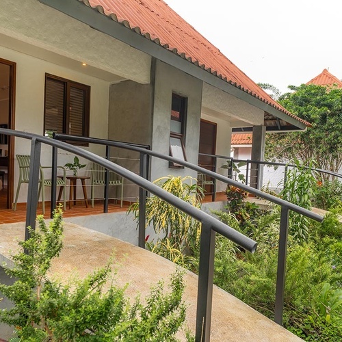 Un conjunto de bungalows con tejados de terracota y rampas con barandales se observa en medio de una exuberante vegetación.