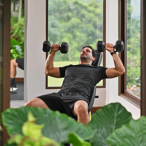Hombre haciendo press de banca con mancuernas en un gimnasio con vista a la selva, Alto Monte