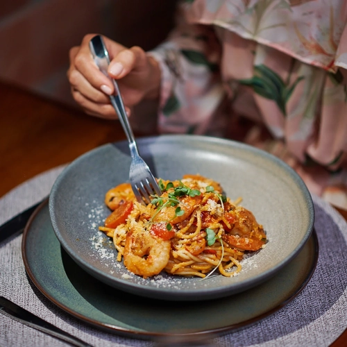 Plato de pasta con gambas y tomate, servido con tenedor, perfecto para una cena Alto Monte.