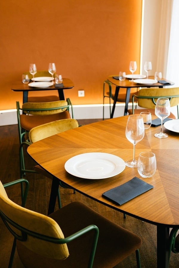 Ambiente de jantar elegante no Hotel AndTales, com mesas de madeira e cadeiras estilosas.