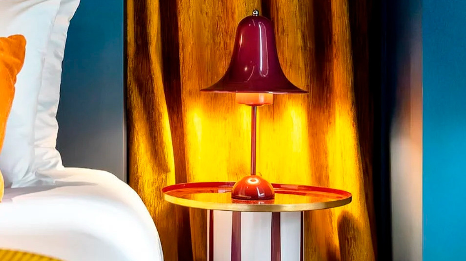 Abajur AndTales e mesa listrada em quarto elegante com cortinas douradas.