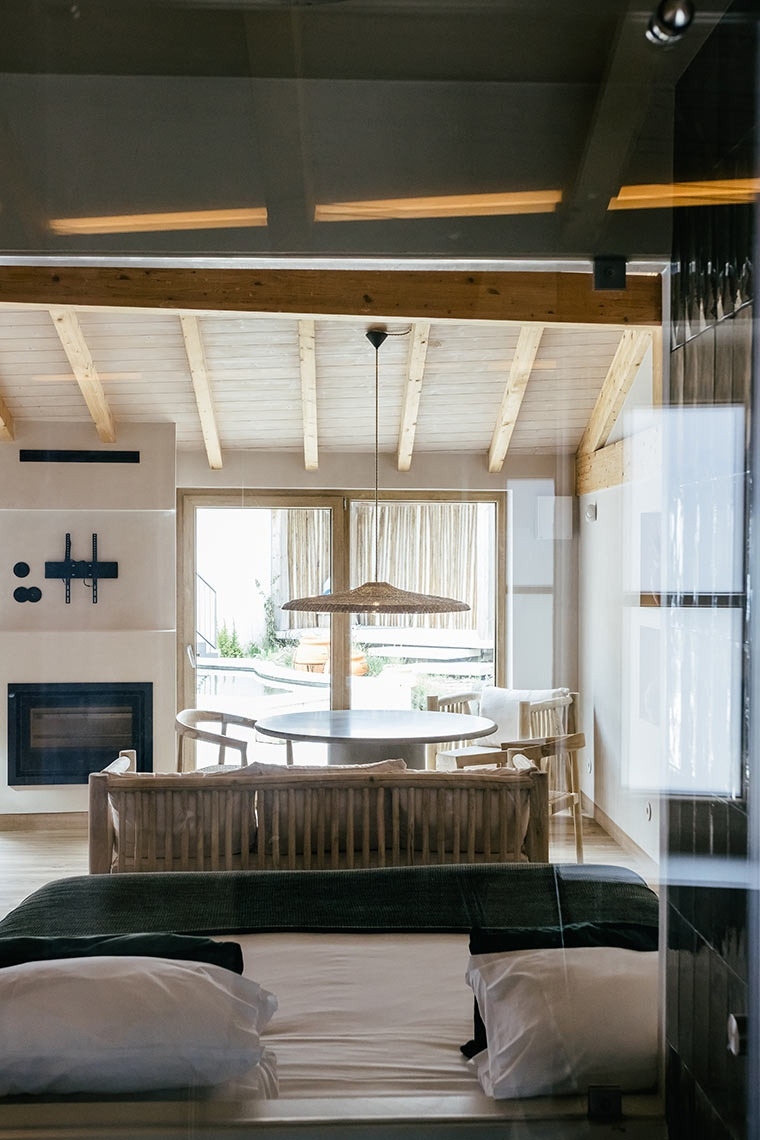 Interior of a spacious hotel suite at AndTales, featuring a bedroom, dining area, and fireplace.