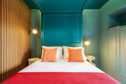 Quarto AndTales com cama, almofadas laranjas e decoração moderna.